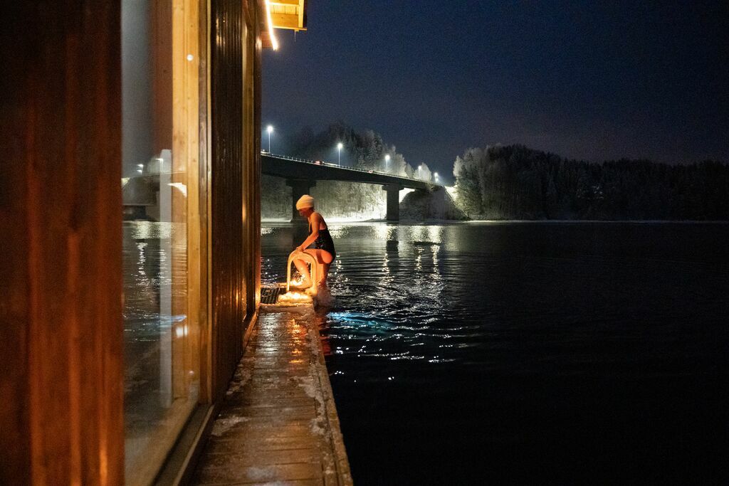 Image of a woman in bathing suit exiting the water and into a sauna